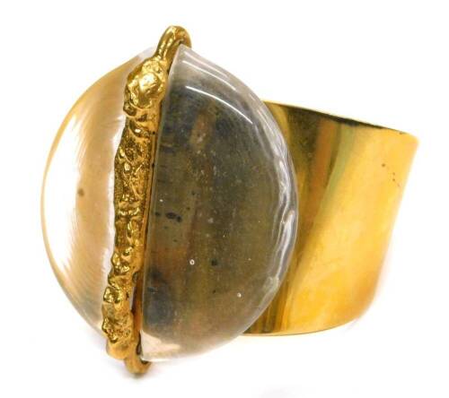 A Jacob Hull of Denmark bangle, of modern abstract design with central clear stone set panel, with gold coloured stem to centre, on gold coloured bangle bracelet, marked B&D, Jacob Hull Denmark.