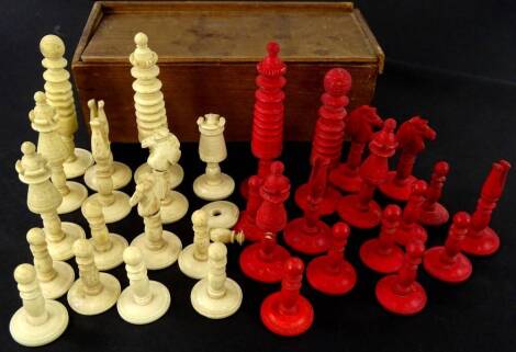 A late 19thC carved bone chess set, part stained red, height of King 9cm high.