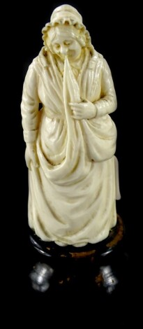 A 19thC carved ivory figure of a lady wearing a bonnet and a long dress, possibly Dieppe, on an ebonised base, 13cm high.