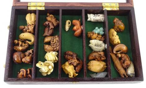 A collection of late 20thC bone, resin and carved wooden netsuke, in Japanese style, and a glazed display case, 38cm x 23cm.