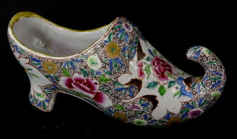 A French faience model of a shoe, decorated in famille rose enamels, makers stamp D and a flowerhead to the underside, 18cm wide.