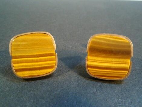 A pair of cuff links set with tigers eye agate