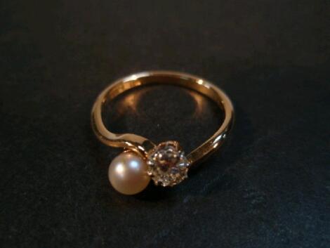 A ladies dress ring, a small diamond and pearl bead in crossover setting stamped 18ct