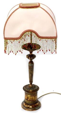 A copper lamp base with fluted and beaded decoration, with a silk shade with beaded tassels, 72cm high overall.