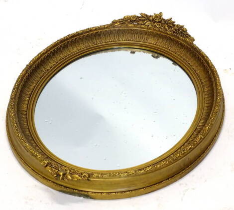 A late 19th/early 20thC oval gilt gesso wall mirror, decorated with flowers, leaves etc., 82cm x 67cm. Provenance: The Estate of Miss Rachel Monson.