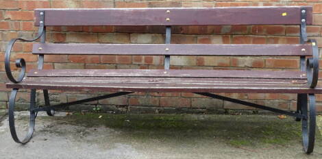 A slatted garden bench, with ebonised wrought iron ends, 173cm wide.