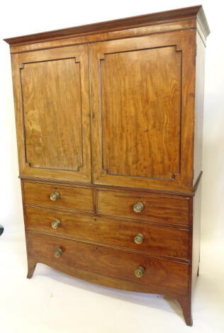 An early 19thC mahogany clothes press, the top with a moulded cornice above two panelled doors, enclosing sliding tray, the base with two short and two long drawers, each with brass handles on splay feet, 186cm high, 135cm wide.