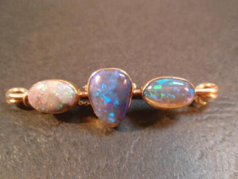 A bar brooch set with three opals in yellow metal