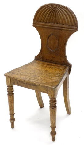 An early 19thC mahogany hall chair, the shaped back, solid seat, on turned tapering legs.
