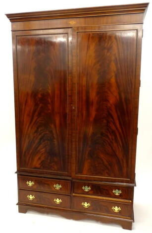 A mahogany wardrobe, with a moulded cornice oval and circular pattera inlaid frieze, above two panelled doors enclosing a hanging rail, the base with four drawers on bracket feet, 115cm high, 135cm wide.