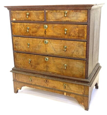 An 18thC walnut chest on stand, the top with a moulded cornice with two short and three long cross banded drawers, with brass tier drop handles, the base with a single frieze drawer on bracket feet, adapted 108cm high, 99cm wide.