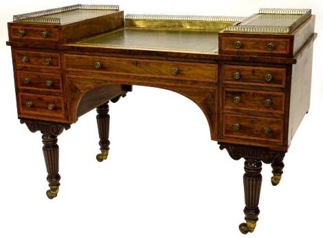 An unusual early Victorian rosewood and satinwood banded desk, the stepped top with a pierced brass gallery and three green tooled leather inserts, above an arrangement of four drawers and a frieze drawer, on fluted turned tapering legs, with castors, ced