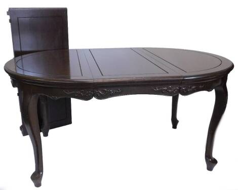 An oriental hardwood extending dining table, the rectangular top with a moulded edge and rounded ends, above a frieze carved with scrolls, on cabriole legs with tapering feet, two loose leaves and a set of nine matching chairs, each with a solid splat, dr