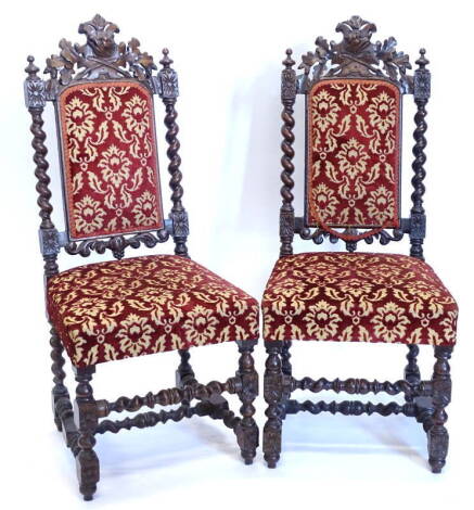 A pair of late Victorian carved oak side chairs, each decorated with a balls head type crest, on spirally turned supports with a padded back and seat, in red and gold velvet. Provenance: The Estate of Miss Rachel Monson.