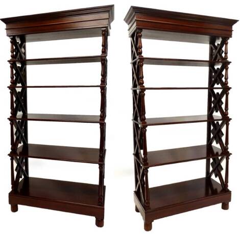 A pair of hardwood open stands or bookcases, each with a moulded cornice on turned supports with X shaped dividers, with five graduated shelves, each with a moulded edge, and bun feet, 213cm high, 103cm wide.