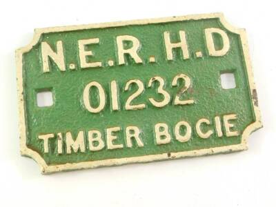 A cast iron North East Railway wagon plate, white painted high relief against a green ground, 'N.E.R.H.D. 01232'., timber bogie, 22cm wide.