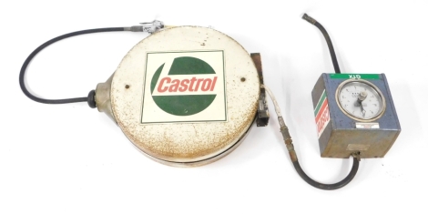 A Castrol wall mounted oil dispenser, with circular dial for litres dispensed, with extendable hose in white painted metal holder, and red and green Castrol decals.