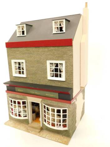 A three storey doll's house, with haberdashery shop "Lillien Baxter", with fitted interiors and dolls, 46cm wide, 37cm deep, 69cm high.