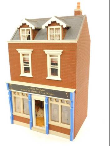 A two storey doll's house, with Wilkin's Micaber & Co books and tearooms, two storey, with fitted interior and dolls, 40cm wide, 30cm deep, 70cm high.