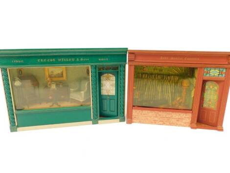 Two doll's house shop window fronts, comprising 'Kyme Musical Emporium', 31.5cm wide, 25.5cm high, and 'Ernest Willow & Sons Cabinet Makers', 38cm wide, 26cm high. (2)