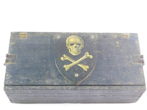 A magician's wooden box, containing conjuring tricks, jokes, etc., the lid bearing a shield with skull and crossbones.