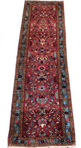 A Hammadan carpet runner, with stylised floral central field on red ground, enclosed by triple borders, with a turquoise central band, 320cm x 92cm.