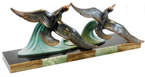 An Art Deco figural of two birds in flight, on a green, brown and black onyx base, 70cm wide.