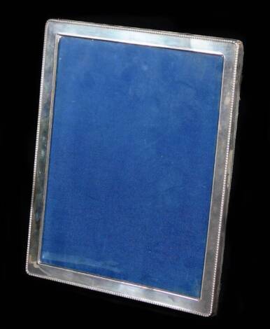 An Elizabeth II silver photograph frame, of oblong form with a bead outline, plain interior and material easel back, Sheffield 1990, 29cm x 24cm.