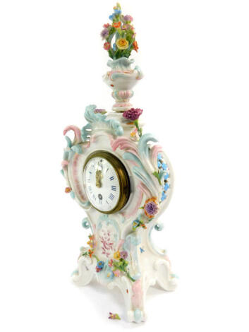 A German late 19thC porcelain cased mantel clock, circular enamel dial bearing Roman and Arabic numerals, thirty hour movement, the case of rococo balloon form, with a vase of flowers finial encrusted with flowers and painted with flowers and insects, A R