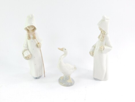 A pair of Lladro porcelain figures, modelled as girls with basket in a hooded garment, 22cm high, together with another Lladro porcelain figure of a duck. (3)