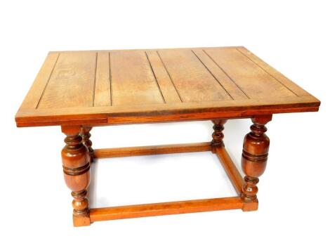 A 17thC style oak draw leaf dining table, raised on cup and cover supports, united by a box stretcher, 75cm high, 137cm wide, 213cm extended, 106.5cm deep.