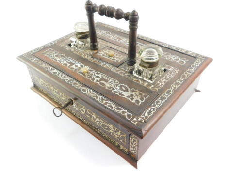 A Victorian rosewood and mother of pearl inlaid desk stand, of rectangular section, with two pen boxes, a pair of cut glass inkwells flanking a central stamp box, over a frieze drawer, raised on a plinth base, 29.5cm wide, 23.5cm deep. (AF)