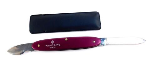 A Patek Philippe watch repairer's folding pocket knife, purple metal cased with two blades, and sheath, 8.5cm wide.