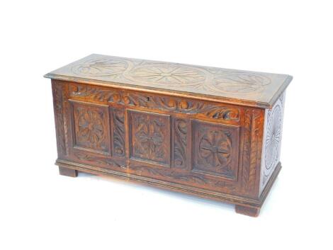 A 17thC style oak blanket chest, with a floral and leaf carved hinged lid, and similarly carved triple panel front, raised on block feet, 53cm high, 106.5cm wide, 45cm deep.