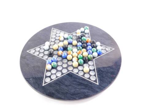 A Taiwanese black marble solitaire board, with glass marbles, board 30.5cm diameter.