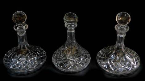 A near pair of cut glass ship's decanters and stoppers, 27cm high, and a further ship's decanter and stopper, 24cm high. (3)