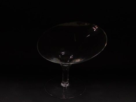 A contemporary glass pedestal fruit bowl, with an abstract bowl, raised on a cylindrical stem over a conical foot, 23cm high.