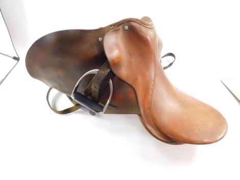 A tan leather riding saddle, with stirrups, and bridle straps. (a quantity)