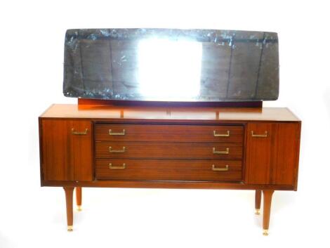 A G Plan teak dressing table, the oblong mirror over three long drawers, flanked by a pair of cupboard doors, raised on tapering legs, brass capped, 156cm wide, 43cm deep, 123cm high.