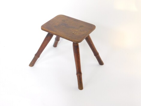 A 19thC elm and oak milking stool, the rectangular top raised on four turned splayed circular legs, 36cm wide, 28cm deep, 26.5cm high.