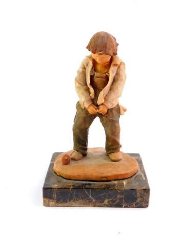 A resin sculpture of a boy relieving himself, signed indistinctly, raised on a rectangular veined brown marble base, 14cm wide, 22cm high.