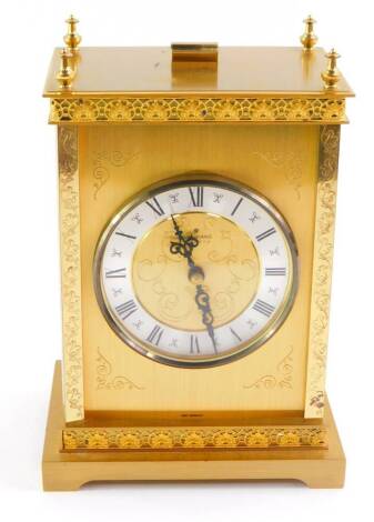 A Junghans brass cased carriage clock, the circular dial with silvered chapter ring bearing Roman numerals, quartz movement, the case with engraved foliate and overlay damascened decoration, raised on bracket feet, 15.5cm wide, 11cm deep, 20cm high.