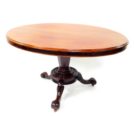 An early Victorian mahogany oval tilt top breakfast table, raised on an hexagonal column and turned cylindrical base, with three cabriole legs, on castors, 70cm high, 98cm wide, 132cm deep.