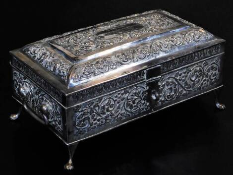 An early 20thC Indian ceremonial freedom casket, of rectangular compressed sarcophagus form, heavily repousse decorated with an outline of scrolls and flowers, with side handles, on compressed hairy paw feet, with further panels of repousse decorated scro