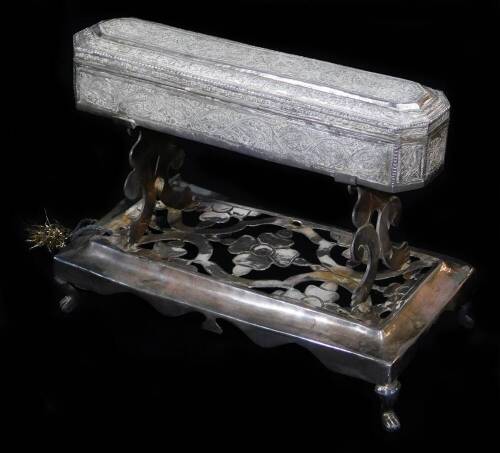 An early 20thC ceremonial freedom casket on stand, heavily chased with a repeat scroll floral pattern, on a pierced stand, terminating in turned hairy paw feet, Indian white metal, unmarked, 19cm high, 25cm wide, 13cm deep.