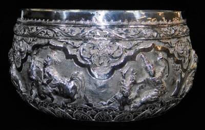 An early 20thC Indian ceremonial bowl, heavily repousse decorated with figures scrolls and flowers, with further hammered decoration, on a plain base, Indian white metal, unmarked, 8cm high, 15cm diameter. - 2