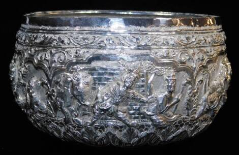 An early 20thC Indian ceremonial bowl, heavily repousse decorated with figures scrolls and flowers, with further hammered decoration, with script mark to the base, Indian white metal, unmarked, 8cm high, 12cm diameter.