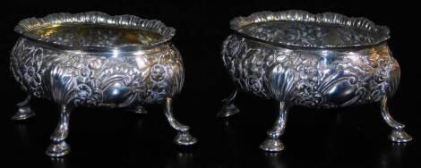 A pair of late 18thC silver salts, of oval form, heavily repousse decorated with a repeat floral pattern, on quadruple hoof feat, possibly 1795, marks badly rubbed, 9cm wide, 6oz. (2)