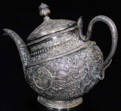 An early 20thC Indian four piece service, comprising shaped tea pot, sugar bowl and jug on an oval tray, each piece heavily repousse decorated with a repeat floral scroll pattern, the tray with an outer pierced border, 36cm wide. (4 pieces) - 5