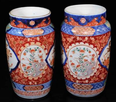 A pair of Imari porcelain vases, each of shouldered cylindrical form decorated with panels of shishi with gilt highlights, further panels of flowers with an upper blue and white geometric border, with panels of flowers, unmarked, 25cm high. (2) - 4